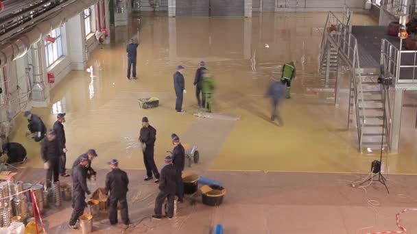 Bouw van een productiehal van binnenuit. Bouwvakkers op een bouwplaats creëren een zelfnivellerende vloer, algemeen plan. Veel arbeiders op de bouw van een werkplaats in een fabriek. — Stockvideo