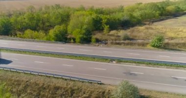 Bir kargo kamyonu otoyol boyunca gidiyor. İnsansız hava aracı görüntüsü. Vagon, tarlaların üst manzarası arasında virajlı bir yolda ilerliyor.