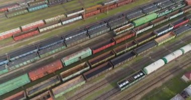 Demiryolu kavşağında bir sürü demiryolu manzarası var. Renkli trenler büyük bir tren istasyonunda duruyor.