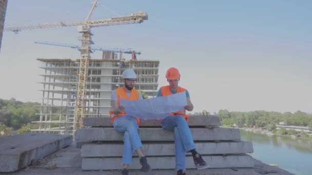 Comiczeichner kreuzen die Beine. Ingenieure vor dem Hintergrund der Baustelle — Stockvideo