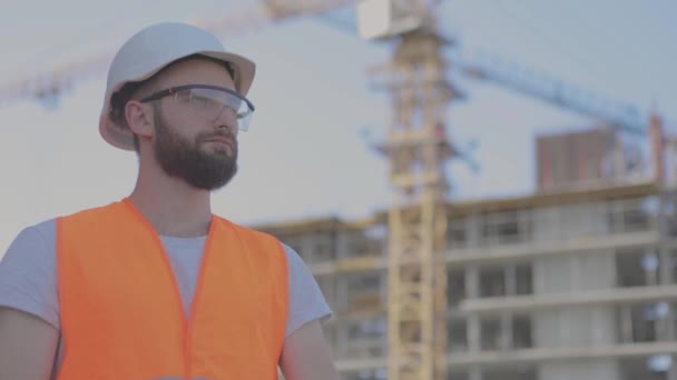 Junger Ingenieur schaut aus nächster Nähe in die Kamera. Ingenieur auf Stryke. Der Bauarbeiter blickt in die Kamera und lächelt — Stockvideo