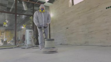 İnşaat alanında çalışma süreci. Koruyucu giysiler içindeki işçiler beton zemini öğütüyor. İnşaat işçileri. İşçiler beton döşeme yapıyor