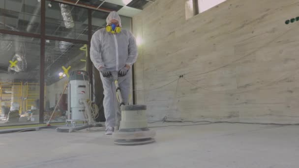 Processus de travail sur un chantier de construction. Les travailleurs en combinaison de protection broient le sol en béton. Professionnels de la construction. Les travailleurs font plancher de béton — Video