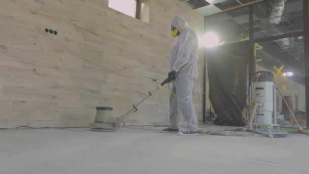 Construction professionals. Working process at a construction site. Workers in protective suits are grinding the concrete floor. Workers make concrete floor — Stock Video