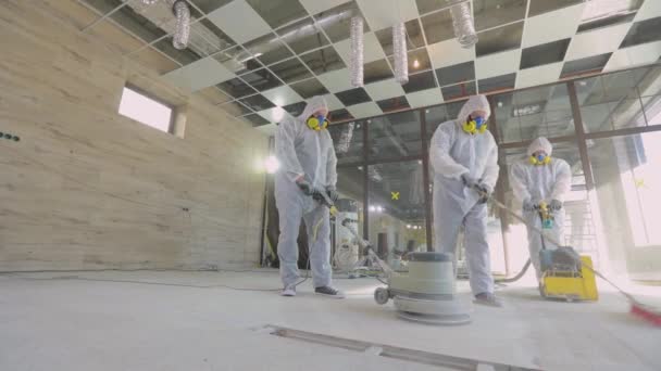 Profesionales de construcción. Proceso de trabajo en una obra. Los trabajadores en trajes de protección están moliendo el suelo de hormigón. Los trabajadores hacen piso de hormigón — Vídeo de stock