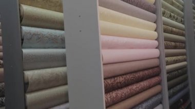 Duvar kağıdı örnekleriyle birlikte dükkanda duruyor. Yeni örneklerle ayakta duruyor. Duvar kağıdıyla yuvarlanıyor. Desenli duvar kağıdı