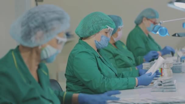 Factory workers pack pills. Masked workers. Workflow at a pharmaceutical factory — Stock Video