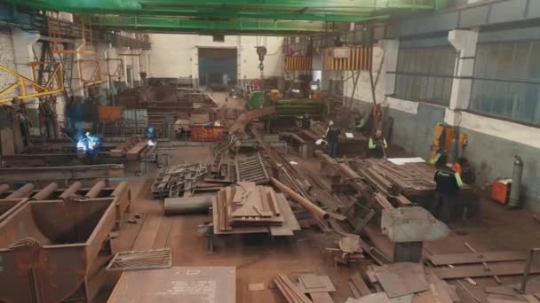 Fabriek voor de montage van metalen constructies. Een lasser in een metaalwerkplaats. Een spanwijdte door de werkplaats voor de montage van metalen constructies. — Stockvideo