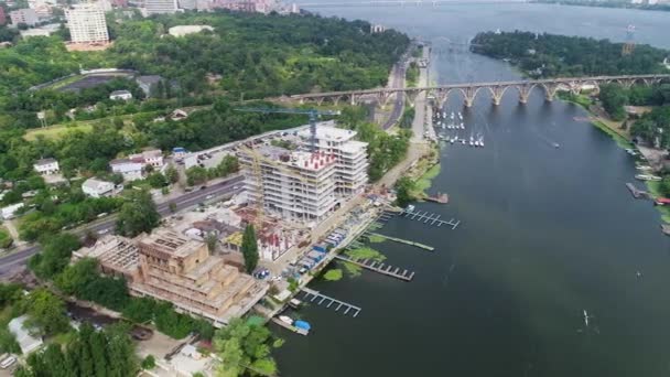 Construção de um complexo residencial perto do rio. Construção de um edifício de apartamentos na margem do rio — Vídeo de Stock