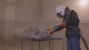 Parçayı zımparalıyorum. Fabrikada metal parçaları kumlamak. Kum püskürtme