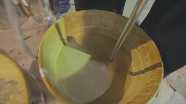 Stirring paint in a bucket. A close-up of yellow paint being stirred in a bucket — Stock Video