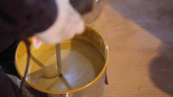 Verf roeren in een emmer. Een close-up van gele verf wordt geroerd in een emmer — Stockvideo