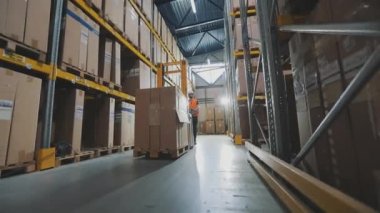 Bir işçi hidrolik forkliftle yük taşır. Büyük, modern bir depo. Stokta modern özel ekipman