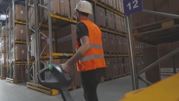 Bir işçi elektrikli forkliftle depoya doğru yürür. Bir işçi depodan kargo taşıyor. — Stok video