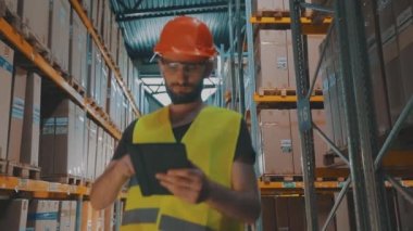 Depoda tabletli bir yönetici malları kontrol ediyor. Büyük bir fabrikanın depo müdürü..