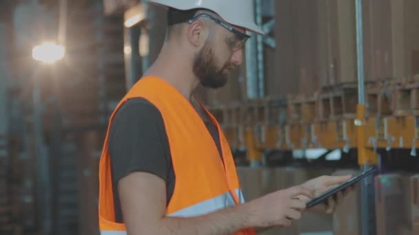 Hombre con tableta en almacén de fábrica. Un trabajador en un almacén hace una ronda. — Vídeo de stock