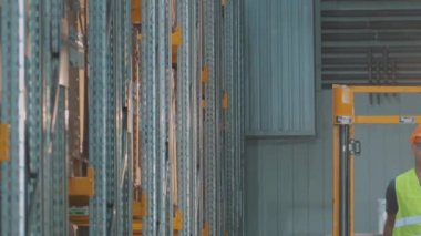 Bir adam ağır çekimde depodan geçiyor. Bir işçi ağır çekimde modern bir depoda yürüyor.