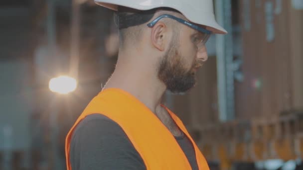 창고 관리인 이 창고를 조사하고 있어. 현대적 인 창고에 있는 남자. 창고에서 헬멧을 쓰고 일하는 노동자 — 비디오