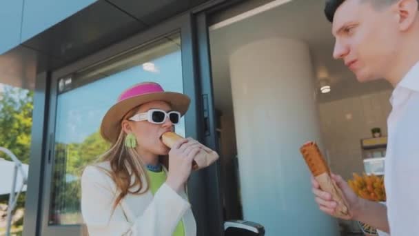 Meisje met een man die hotdogs eet. Stijlvol jong paar eten hotdogs — Stockvideo