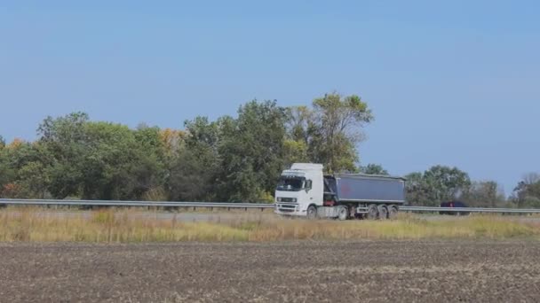 Mavi römorklu bir çöp kamyonu otoyol boyunca gidiyor. Güneşli bir havada uzun bir yolda giden bir kargo kamyonu. — Stok video