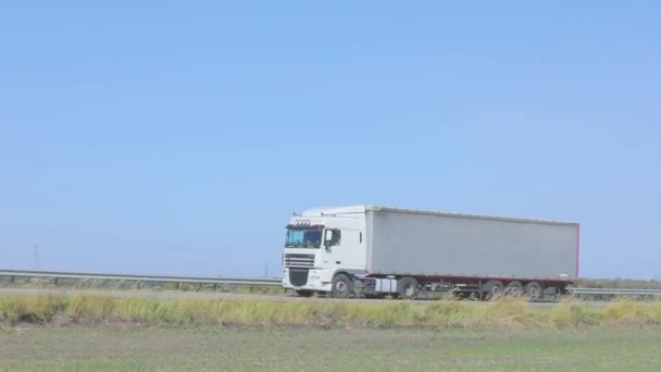 Biały wóz jedzie wzdłuż autostrady w słoneczną pogodę. Ciężarówka na autostradzie — Wideo stockowe