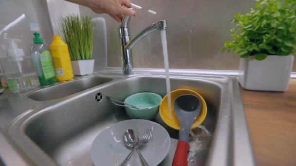 El agua del grifo se vierte en platos sucios. Proceso de lavado de platos. Platos sucios en el fregadero. Rutina en la cocina. Tareas — Vídeo de stock