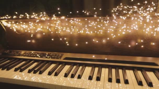 Synthesizer with New Years lights. Beautiful synth with Christmas decorations. Close-up synthesizer keys — Stock Video