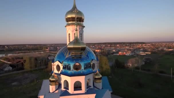 Iglesia ortodoxa en el pueblo al atardecer. Iglesia cerca de la vista aérea del río — Vídeos de Stock