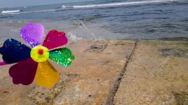 Denizdeki çocuklar yel değirmeni. Çocuklar yel değirmeni. Renkli bir çocuk yel değirmeni kıyıda dönüyor..