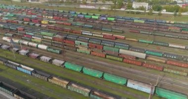 Demiryolu kavşağında bir sürü demiryolu manzarası var. Renkli trenler büyük bir tren istasyonunda duruyor.