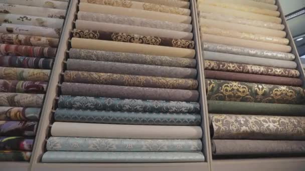 Wallpaper with patterns. Stands with rolls of wallpaper samples in the store. Stands with new samples. Rolls with wallpaper. Closeup — Stock Video