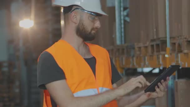 Un manager avec une tablette dans un entrepôt vérifie les marchandises. Directeur d'entrepôt d'une grande usine. — Video