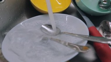 Mutfakta rutin işler. Kirli bulaşıklar lavaboda. Musluk suyu kirli tabaklara dökülür. Bulaşık yıkama işlemi. Ev ödevi