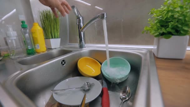 Platos sucios en el fregadero. Rutina en la cocina. El agua del grifo se vierte en platos sucios. Proceso de lavado de platos. Tareas — Vídeo de stock