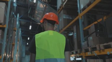 Bir adam ağır çekimde depodan geçiyor. Bir işçi ağır çekimde modern bir depoda yürüyor.