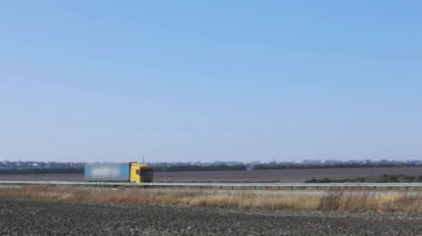 Kamyon otobanda tarlaların ve ağaçların etrafından geçiyor. Kamyon otobanda gidiyor..