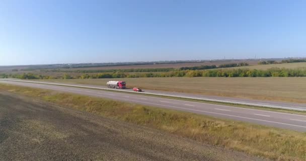 Un camion roule le long d'une belle route entre les champs vue de dessus. Un camion cargo roule le long de l'autoroute. Vue depuis un drone. — Video