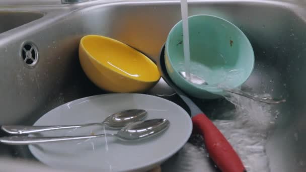 Musluk suyu kirli tabaklara dökülür. Bulaşık yıkama işlemi. Kirli bulaşıklar lavaboda. Mutfakta rutin işler. Ev ödevi — Stok video