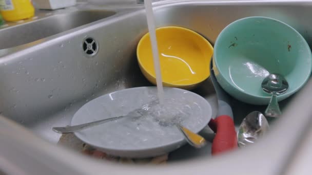 Mocskos edények a mosogatóban. Rutin eljárás a konyhában. A csapvíz piszkos edényekre ömlik. Mosogatási folyamat. Házi feladat — Stock videók