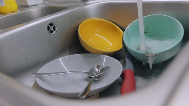 Mosogatási folyamat. Házi feladat. Mocskos edények a mosogatóban. Rutin eljárás a konyhában. A csapvíz piszkos edényekre ömlik.. — Stock videók