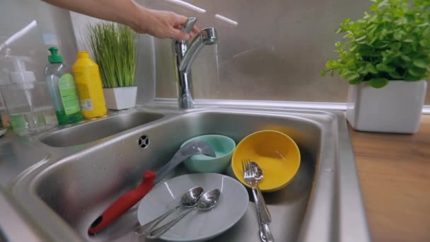 El agua del grifo se vierte en platos sucios. Proceso de lavado de platos. Platos sucios en el fregadero. Rutina en la cocina. Tareas — Vídeos de Stock