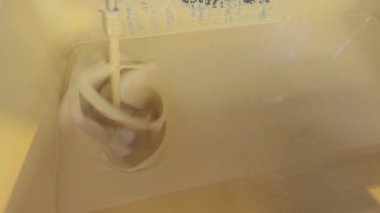 Kovada boya karıştırmak. Yakın plan sarı boya kovada karıştırılıyor.