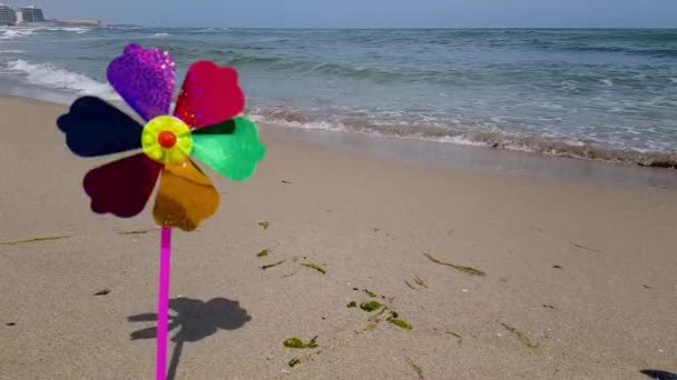 Un moulin à vent pour enfants coloré tourne sur le bord de la mer. Moulin à vent pour enfants en mer. Moulin à vent pour enfants — Video