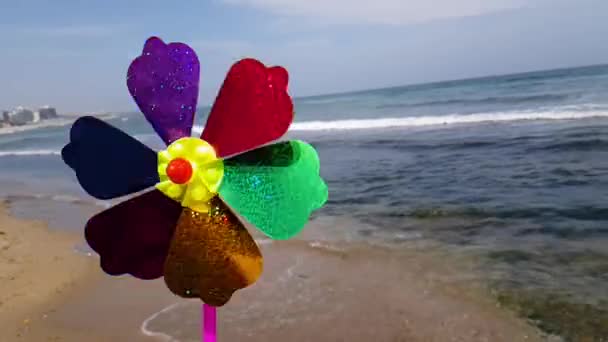 Moulin à vent pour enfants en mer. Moulin à vent pour enfants. Un moulin à vent pour enfants coloré tourne sur le bord de la mer. — Video