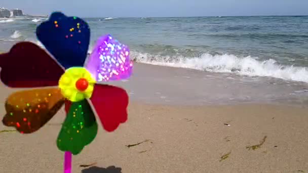 Un moulin à vent pour enfants coloré tourne à partir du vent sur le bord de la mer. Moulin à vent pour enfants sur la mer. Un moulin à vent pour enfants dans le vent — Video