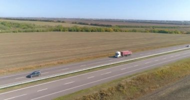 Kamyon tarlaların üst manzarası boyunca gider. Kamyon güneşli havada tarlalar boyunca sürer. Güzel bir yolda kamyon sürüyor.