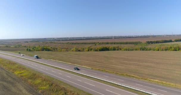 En lastbil kör längs motorvägen. Utsikt från en drönare. Vagnen kör längs en svängd väg mellan åkrarnas övre vy — Stockvideo