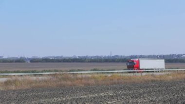 Kırmızı taksisi olan bir kamyon otoban boyunca gidiyor. Kamyon yol boyunca gidiyor. Kamyonla mal teslimatı.