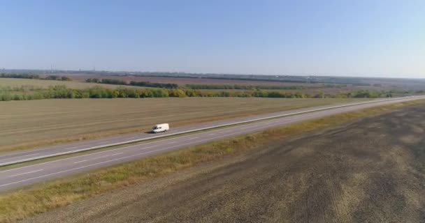 Lastbilen kör längs fälten i soligt väder. Lastbil kör på en vacker väg. Lastbilen kör längs fälten ovanifrån. — Stockvideo