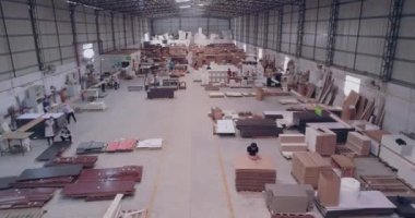 İnsanlar bir mobilya fabrikasında çalışıyor. Mobilya üretimi, mobilya fabrikasının üretim alanının panoram manzarası..